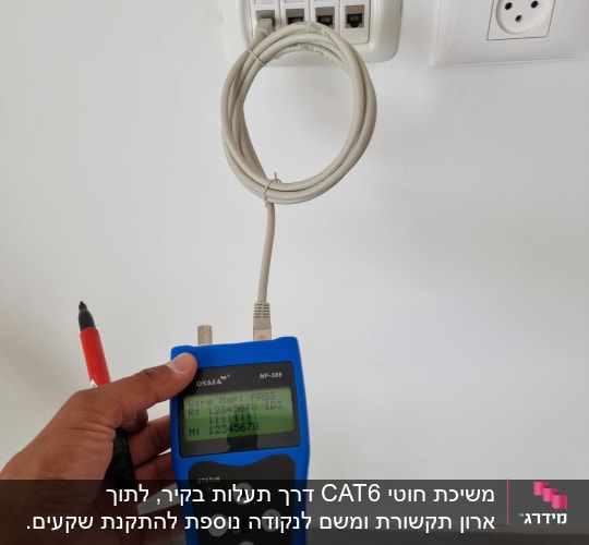 טכנאי רשת בודק כבל עם מכשיר בדיקה כחול